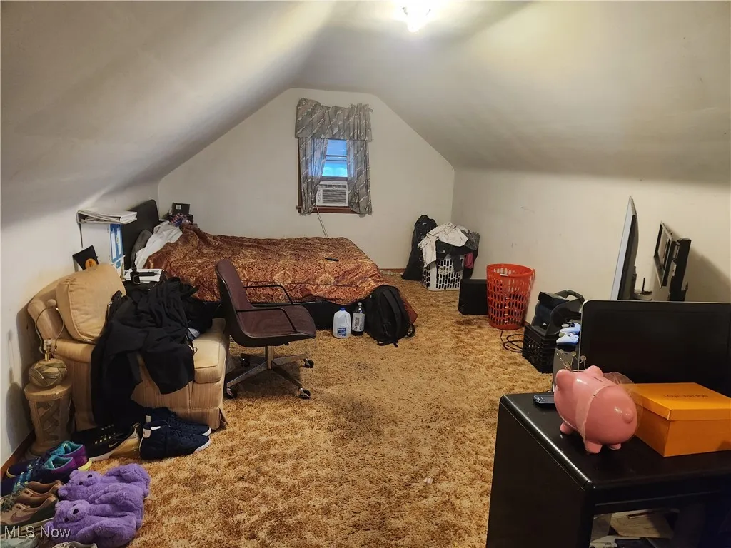 Carpeted bedroom featuring vaulted ceiling and cooling unit