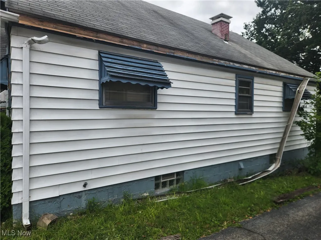 View of side of property with a chimney and a shingled roof