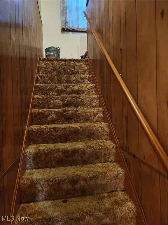 Staircase featuring wood walls