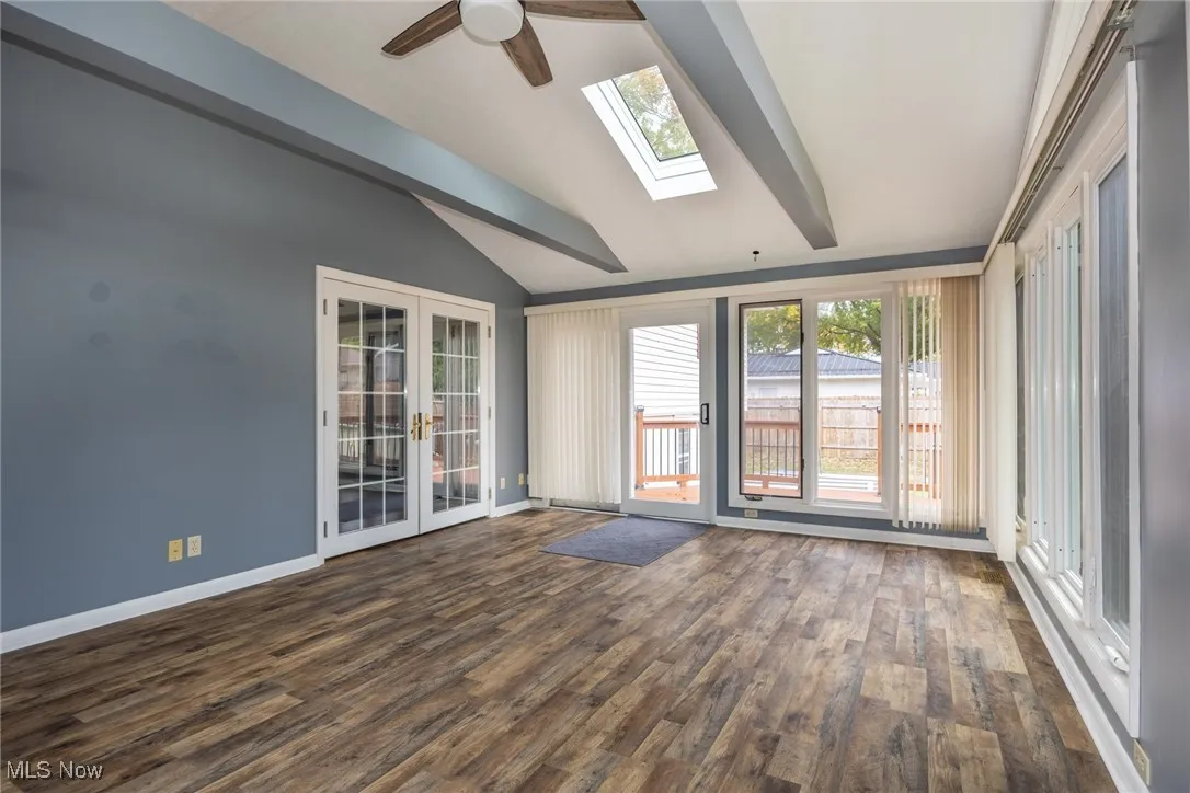 Unfurnished room featuring french doors, ceiling fan, dark wood-type flooring, and a skylight