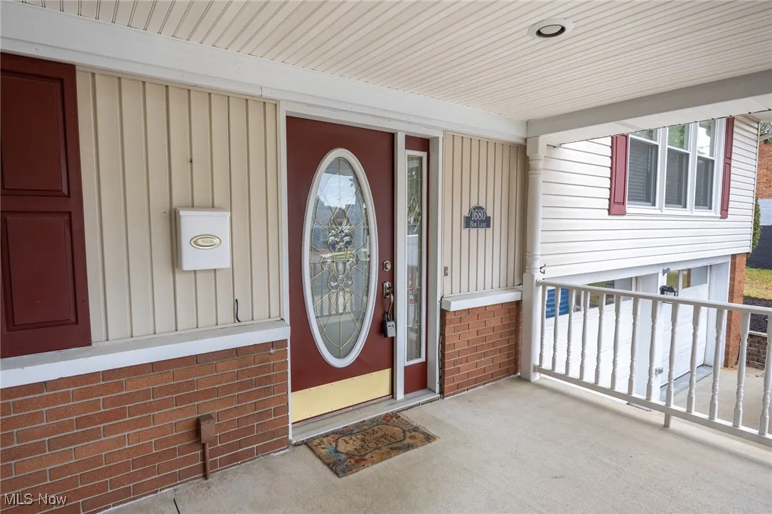 View of exterior entry with board and batten siding and a porch