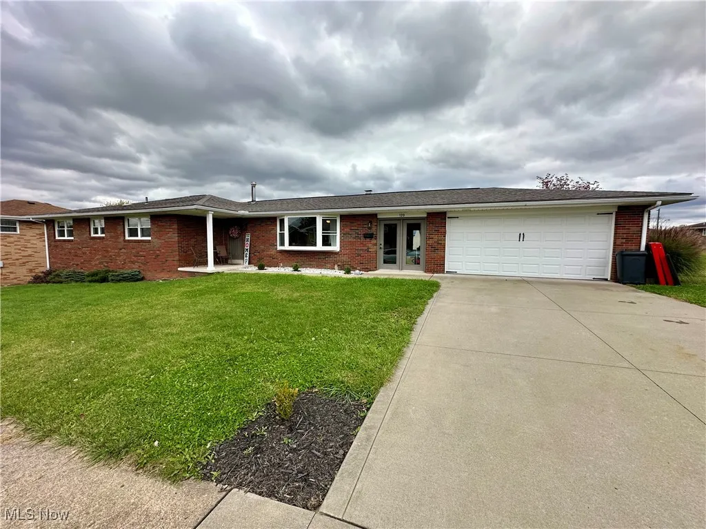 Ranch-style home featuring brick siding, a front yard, concrete driveway, and an attached garage