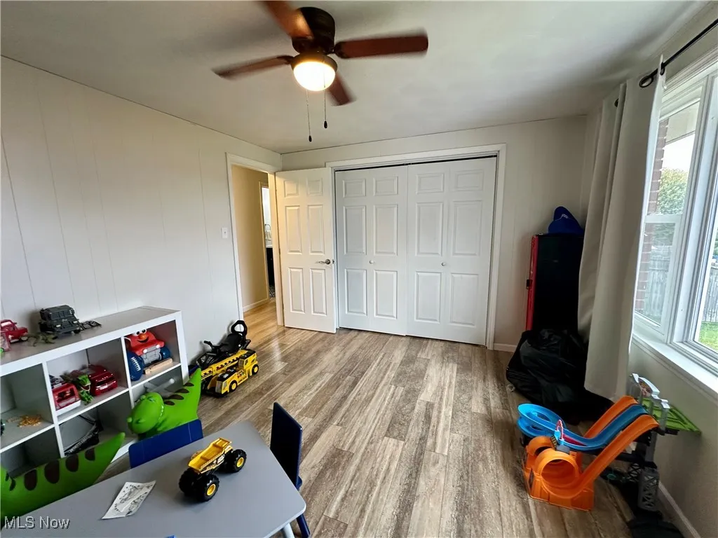Rec room featuring wood finished floors, ceiling fan, and wooden walls