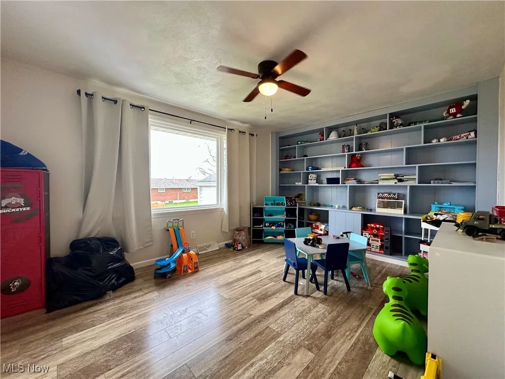 Game room featuring light wood finished floors, a ceiling fan, and a textured ceiling