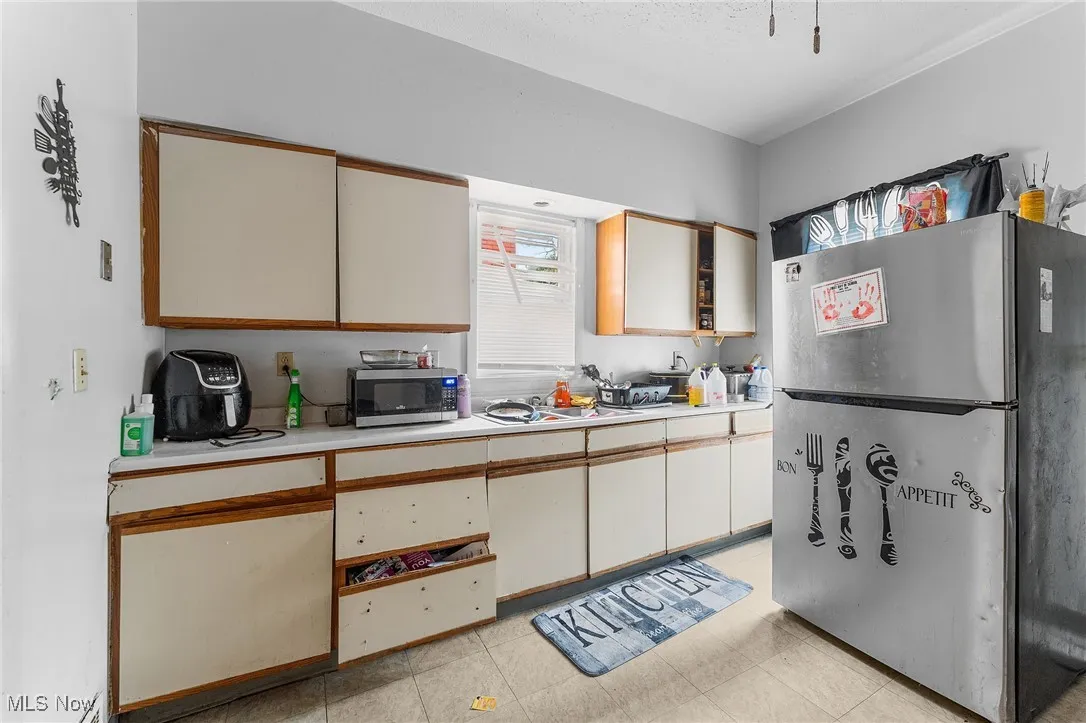 Kitchen featuring light countertops, stainless steel appliances, brown cabinets, and white cabinets