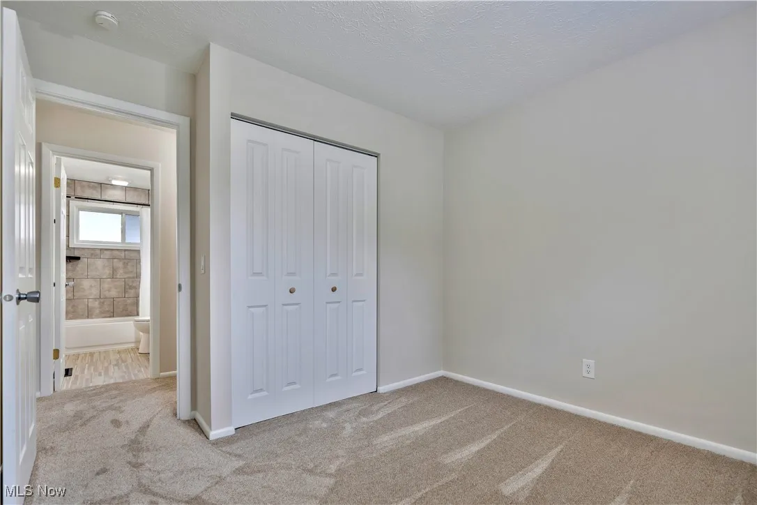 Unfurnished bedroom with carpet floors, a closet, and a textured ceiling