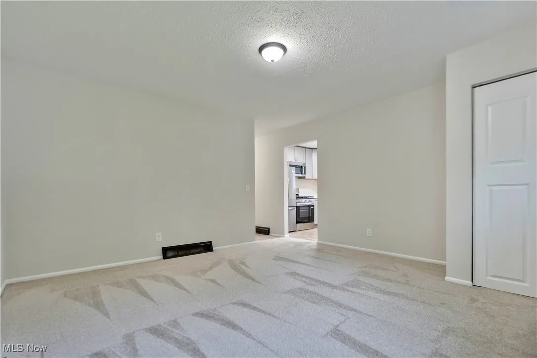 Empty room featuring light carpet and a textured ceiling