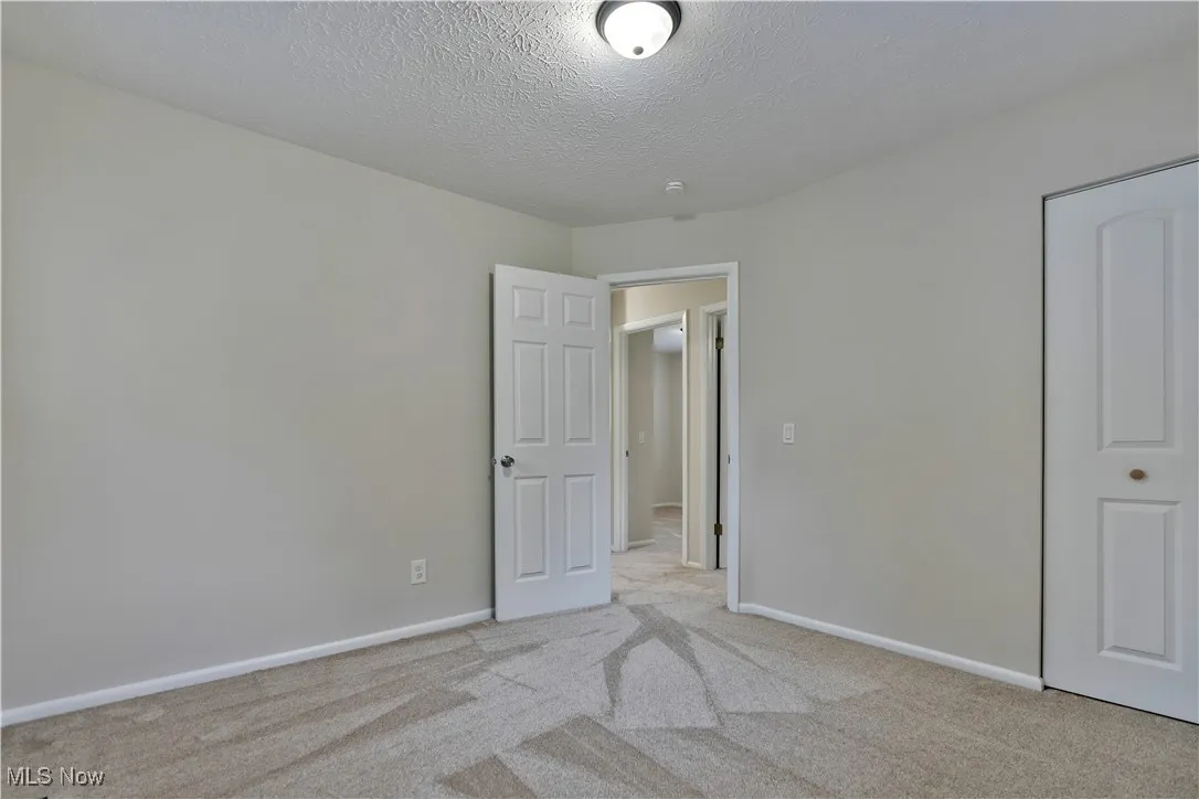 Unfurnished bedroom featuring light colored carpet and a textured ceiling