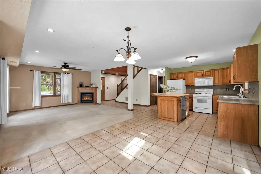 Kitchen with light colored carpet, light tile patterned floors, a chandelier, open floor plan, and hanging light fixtures