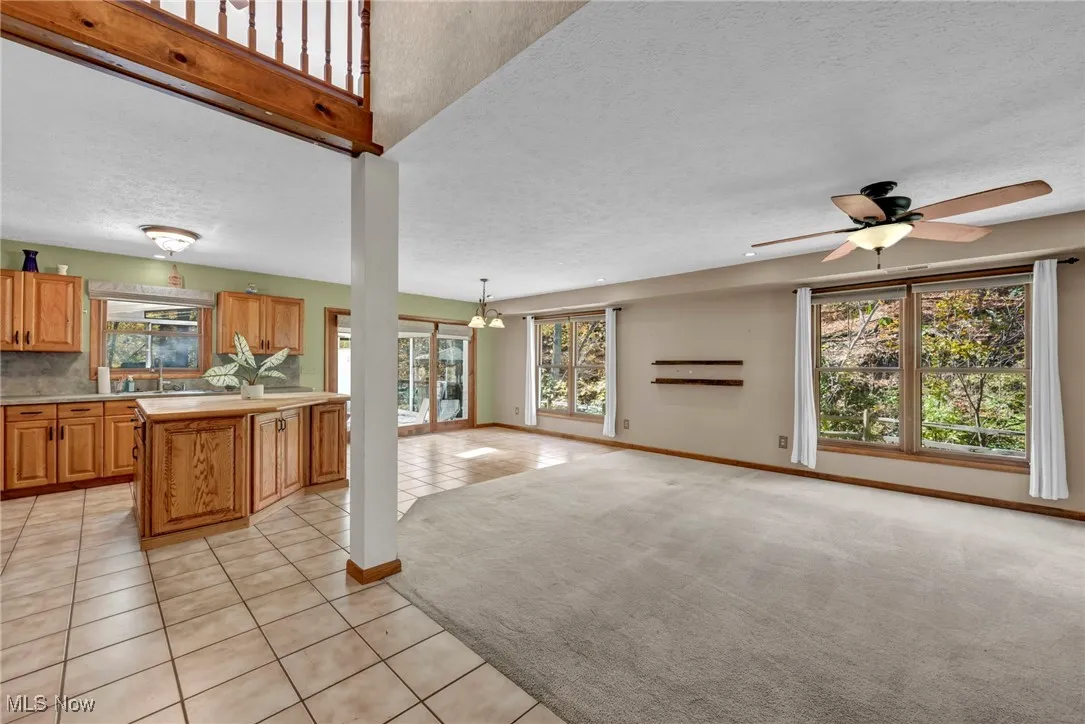 Kitchen featuring a textured ceiling, light countertops, light tile patterned floors, brown cabinets, and open floor plan
