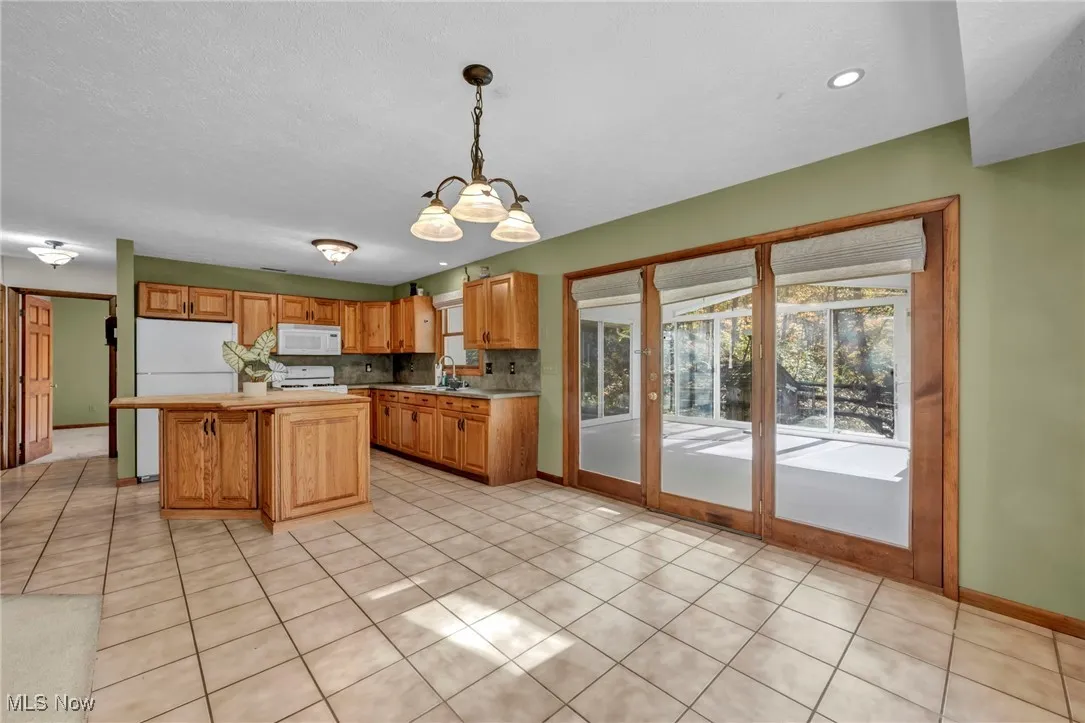 Kitchen featuring decorative light fixtures, light countertops, light tile patterned floors, and white appliances