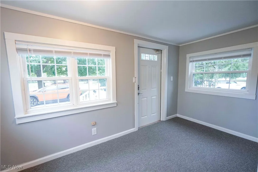 Foyer featuring dark colored carpet and ornamental molding