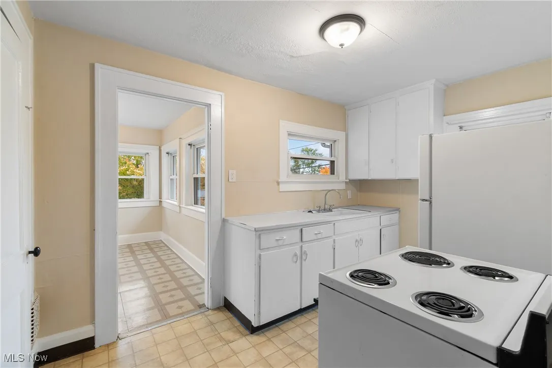 Kitchen featuring white appliances, white cabinetry, light countertops, light floors, and a textured ceiling