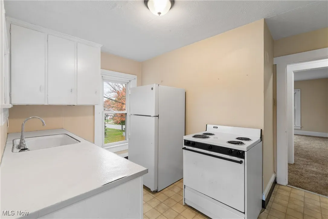 Kitchen featuring white appliances, light countertops, and white cabinetry