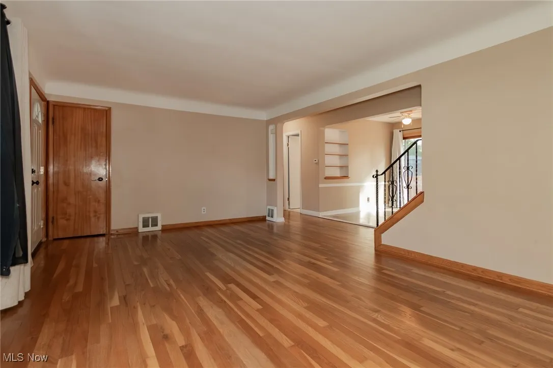 Unfurnished room with wood finished floors, stairs, and ceiling fan