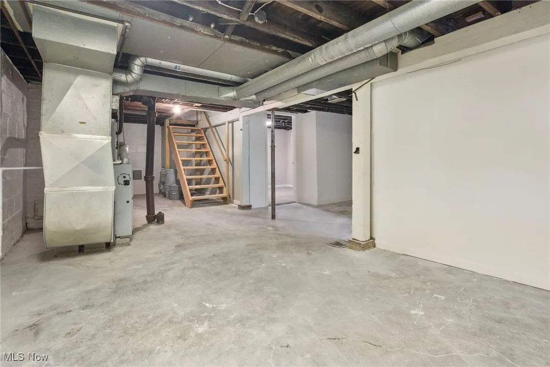 Unfinished below grade area featuring stairs and heating unit