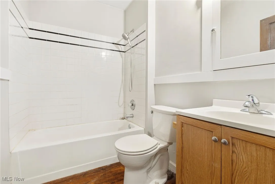 Full bath with dark wood-style flooring, washtub / shower combination, and vanity