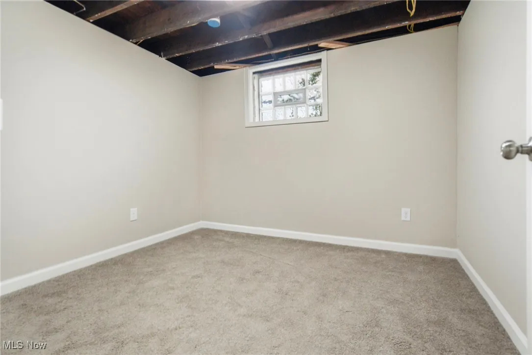 Basement featuring light colored carpet and baseboards