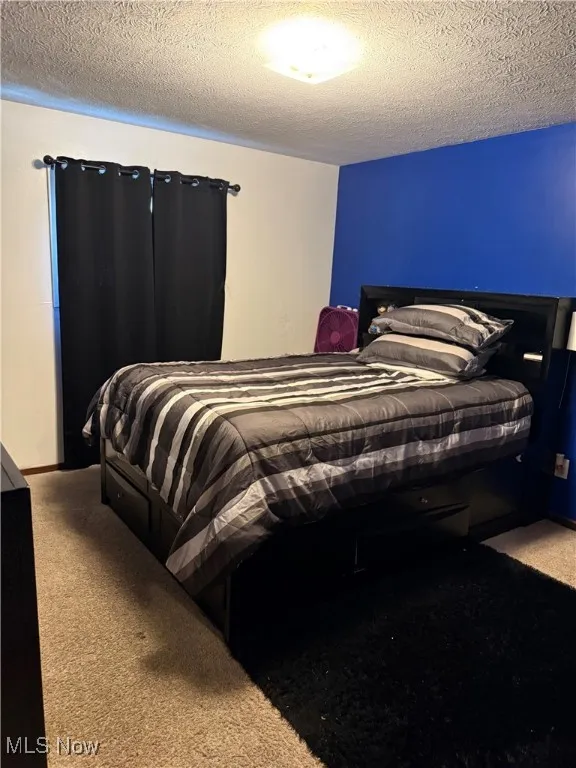 Bedroom with light carpet and a textured ceiling