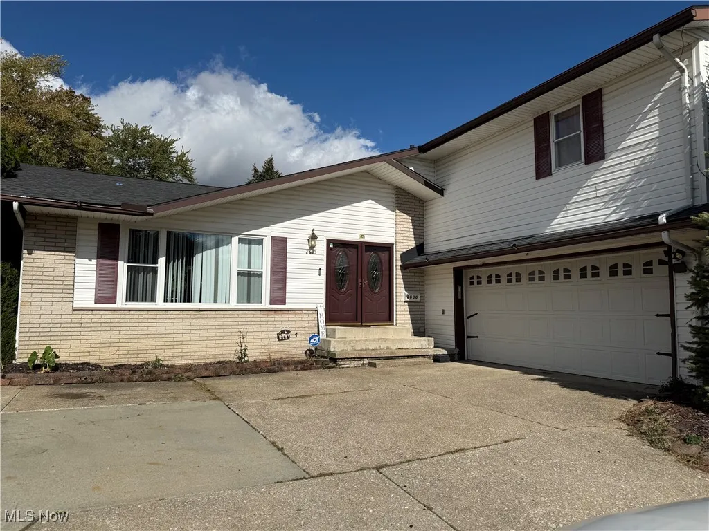 View of front of property with brick siding, concrete driveway, and an attached garage
