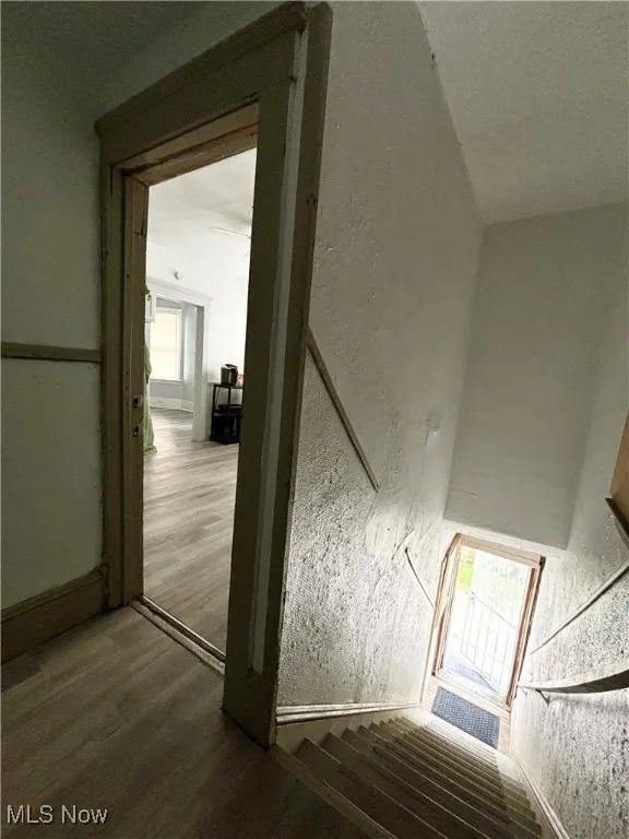 Staircase with wood finished floors and a textured wall