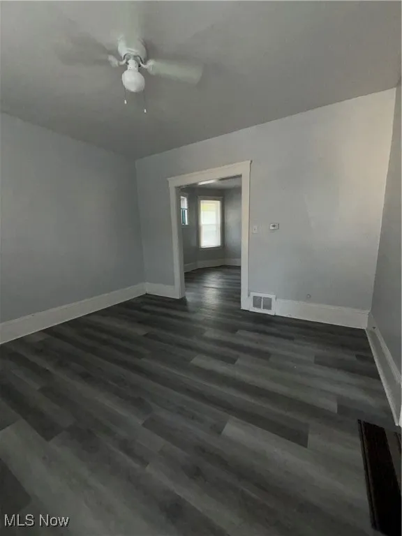 Empty room with dark wood-type flooring and a ceiling fan