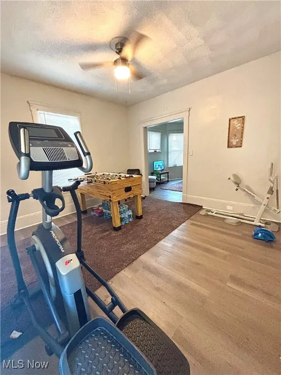 Workout area featuring a textured ceiling, wood finished floors, and ceiling fan