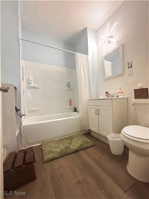 Full bathroom with vanity, dark wood-style floors, and shower / bath combination with curtain