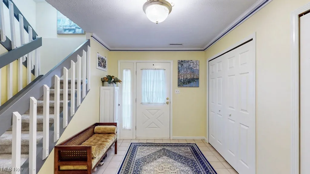 Foyer entrance featuring stairway and light tile patterned floors
