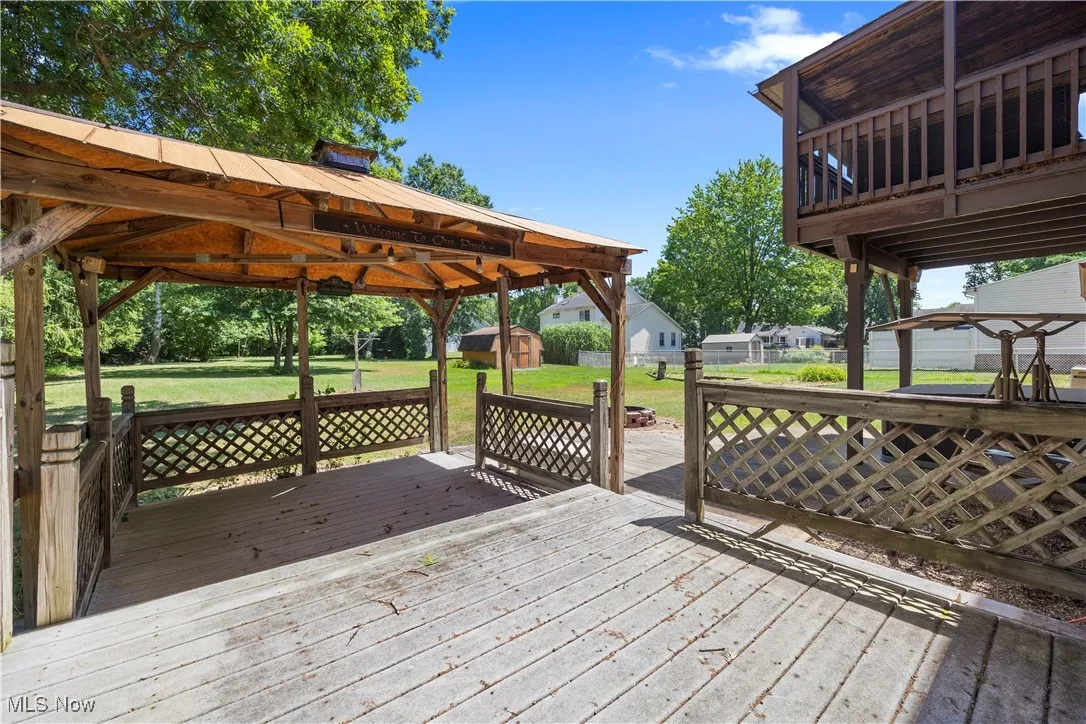 Wooden terrace featuring a storage shed and a lawn