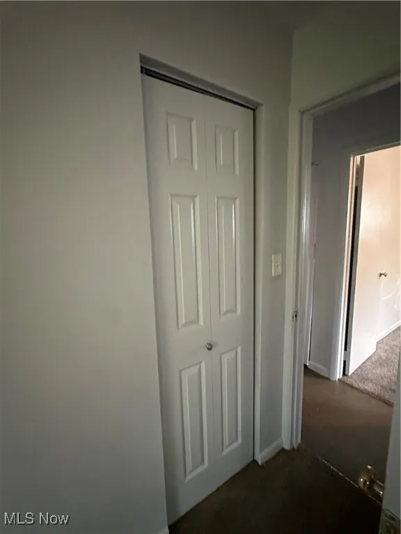 Corridor with dark colored carpet and baseboards