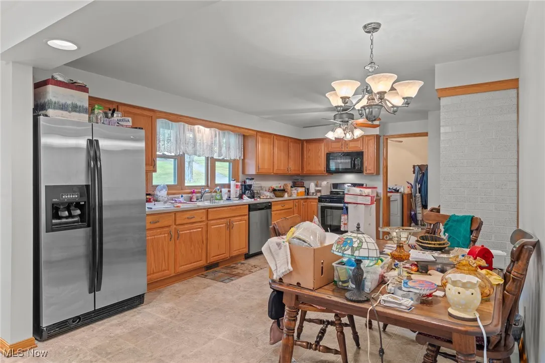 Kitchen featuring stainless steel appliances, light countertops, hanging light fixtures, a chandelier, and brown cabinets