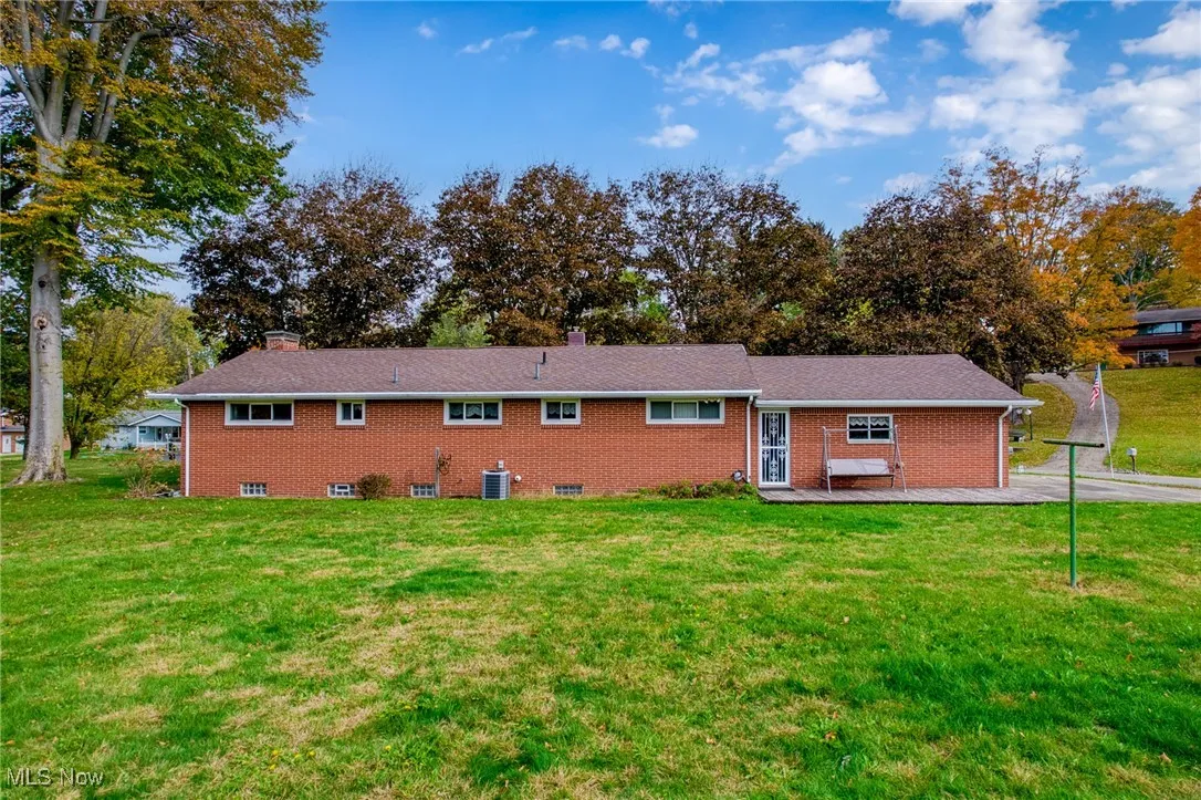 Rear view of property with a lawn, a chimney, and brick siding