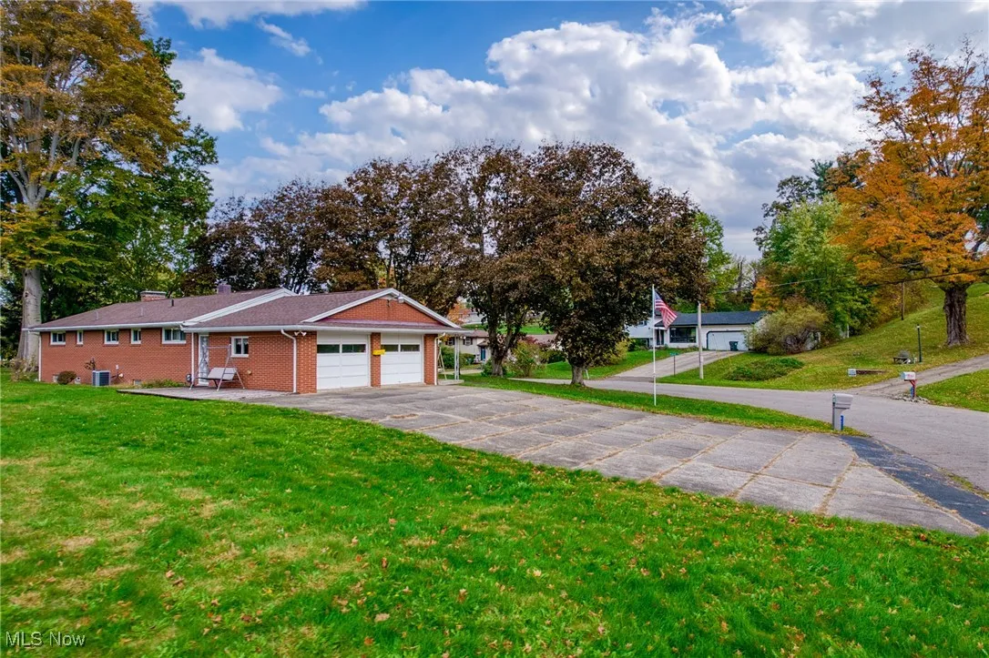 View of front facade with a front lawn, asphalt driveway, brick siding, and a garage