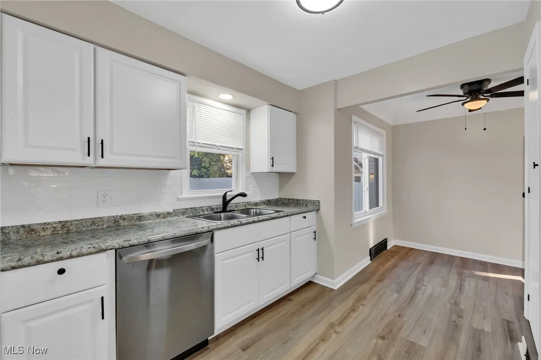 Kitchen featuring stainless steel dishwasher, white cabinetry, light wood finished floors, ceiling fan, and tasteful backsplash