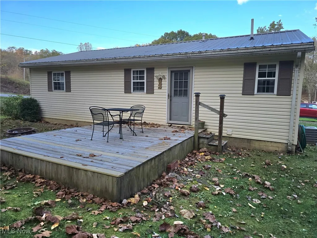 Back of property featuring a metal roof, a deck, and outdoor dining area