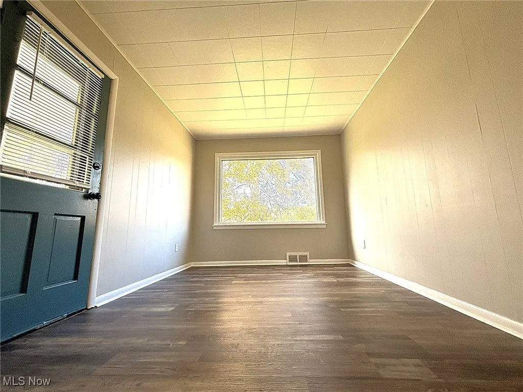 Unfurnished room with dark wood-type flooring and wood walls