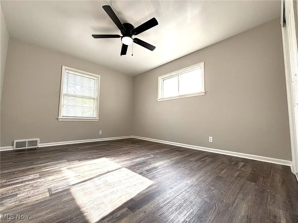 Unfurnished room with dark wood-style flooring and a ceiling fan