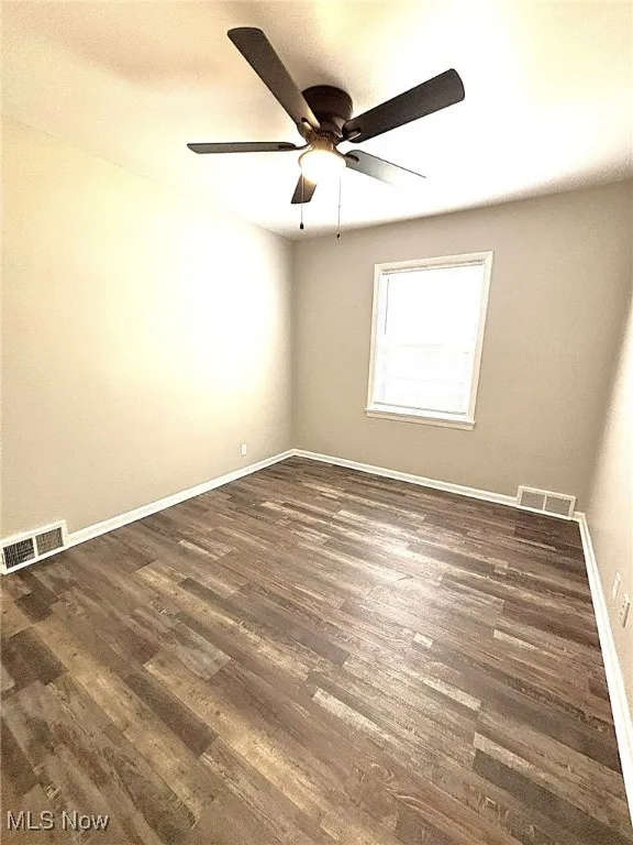 Empty room featuring dark wood-type flooring and a textured ceiling