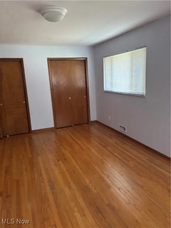 Unfurnished bedroom featuring light wood-style flooring and two closets