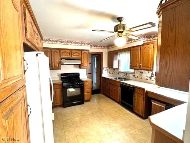 Kitchen featuring black appliances, brown cabinets, light countertops, light floors, and a ceiling fan