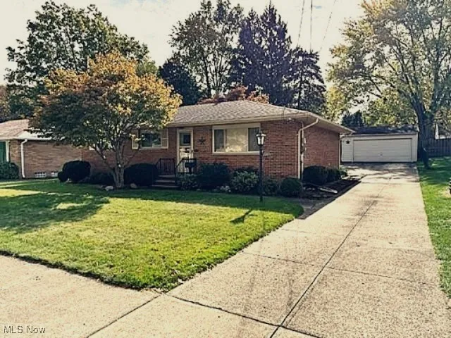 Single story home with a front lawn, an outdoor structure, brick siding, and a garage