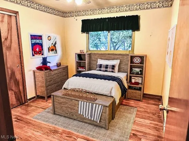 Bedroom with wood finished floors and a closet