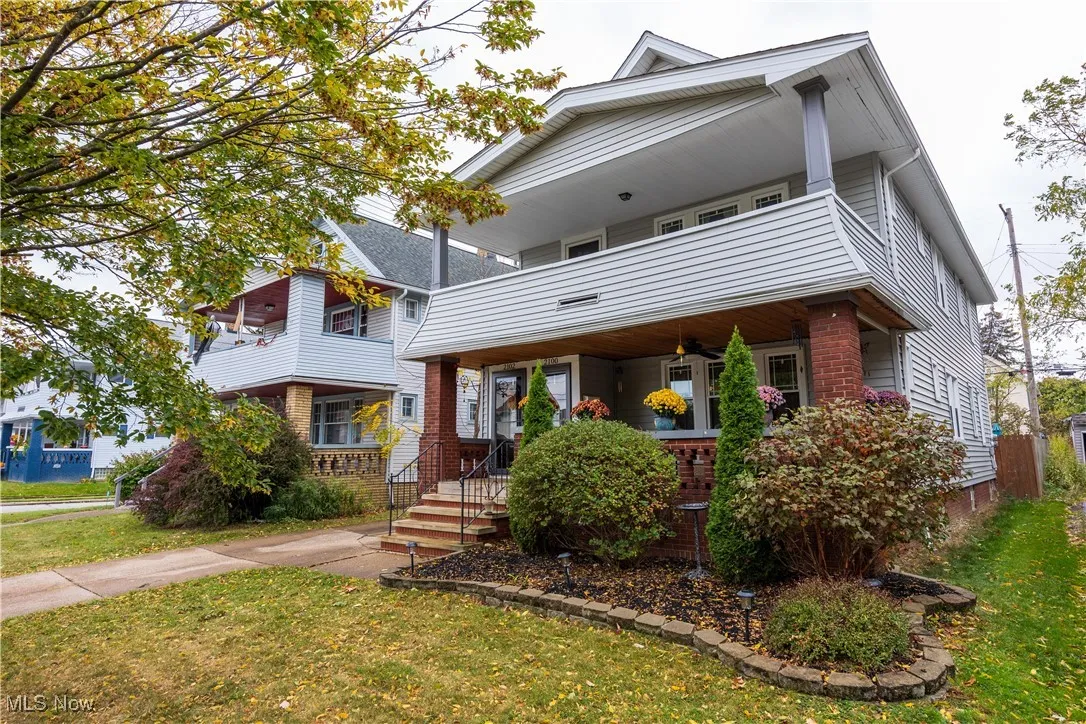 View of front of house featuring a front lawn, a balcony, covered porch, and brick siding