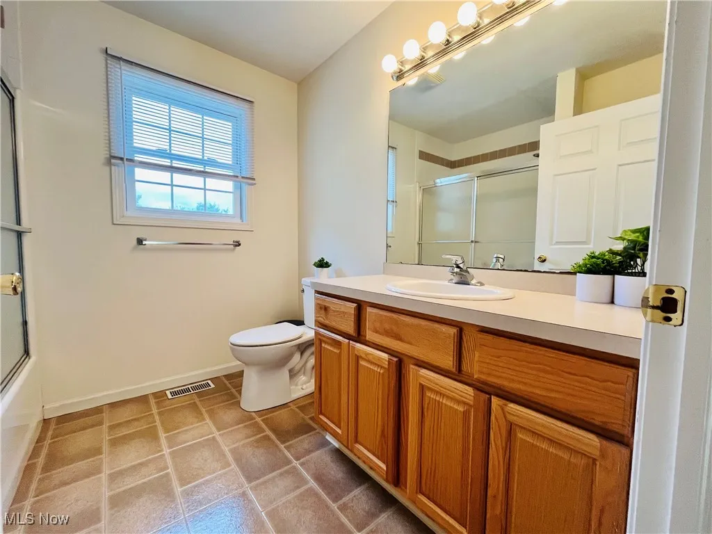 Full bathroom featuring vanity, light tile patterned flooring, and combined bath / shower with glass door