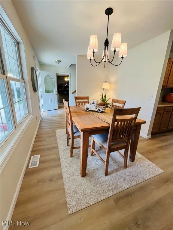 Dining area with light wood-style floors and a chandelier