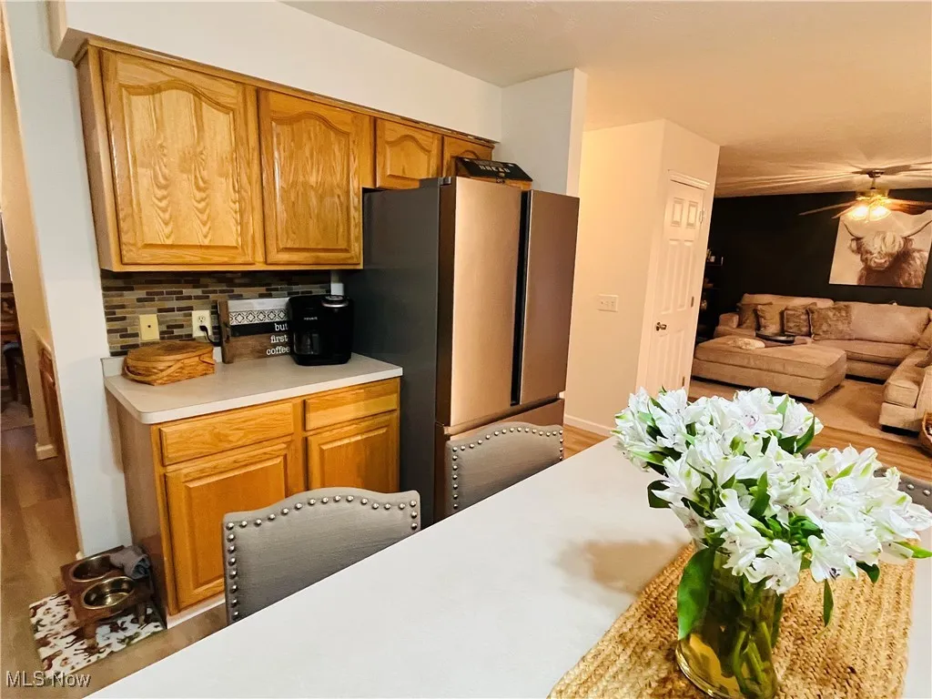 Kitchen featuring light countertops, brown cabinetry, a ceiling fan, and freestanding refrigerator
