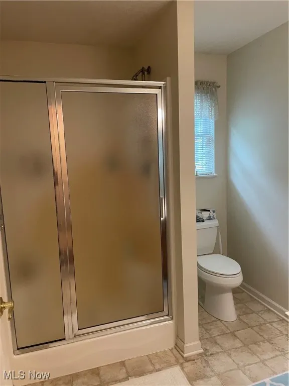Full bath featuring a stall shower and baseboards