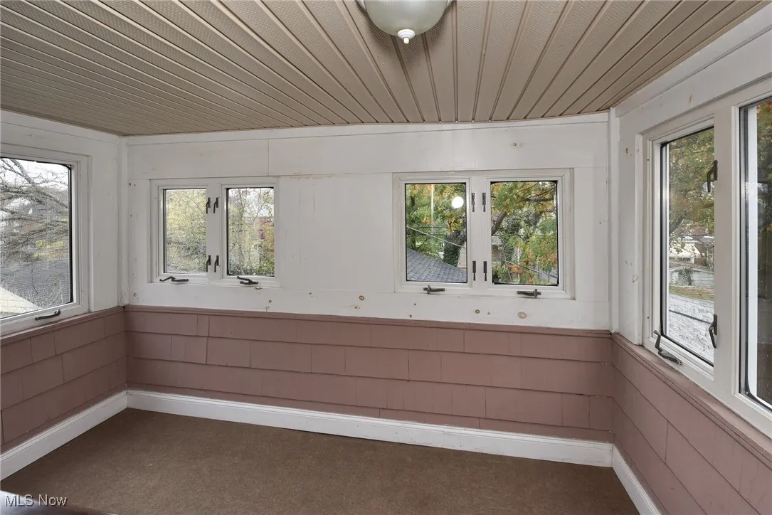 Unfurnished sunroom with wood walls, carpet, and wooden ceiling