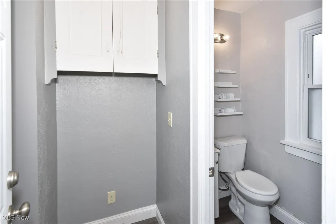 Bathroom with a textured wall and dark wood-type flooring